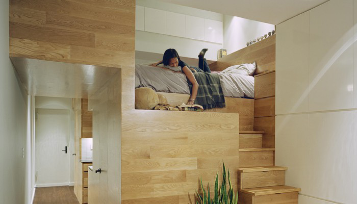 A wooden loft bed in a tiny apartment.