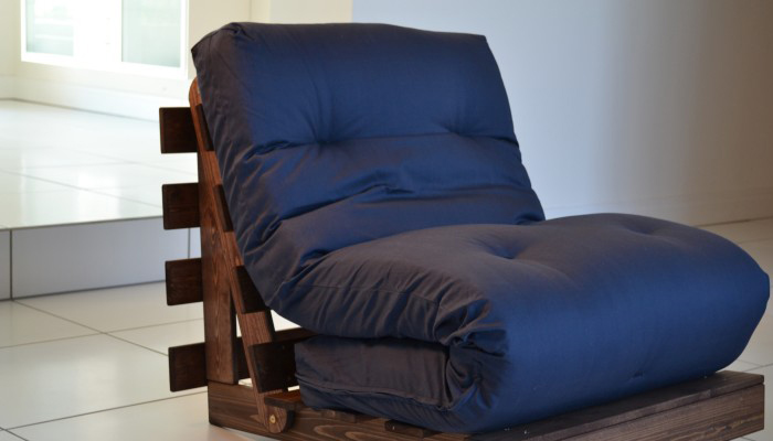 A blue futon folded up onto a brown DIY wood pallet chair.