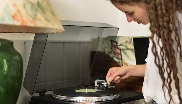 a woman setting up vinyl record player 