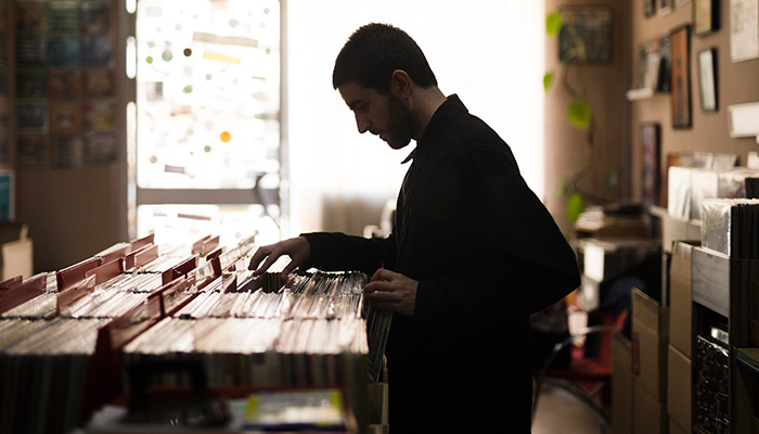 Medium shot side view of a young man looking for vinyl in-store