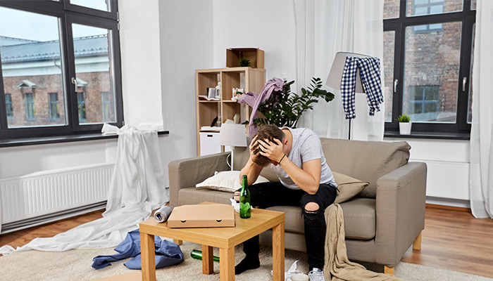 stressed man sitting in a messy room