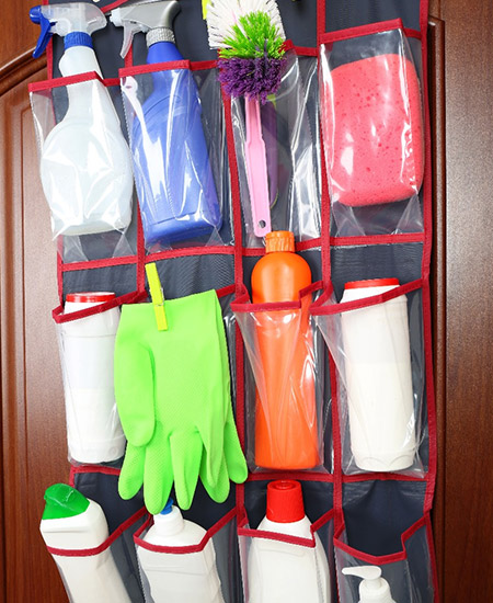 DIY pocket organizer hanging on a cabinet door and storing cleaning supplies