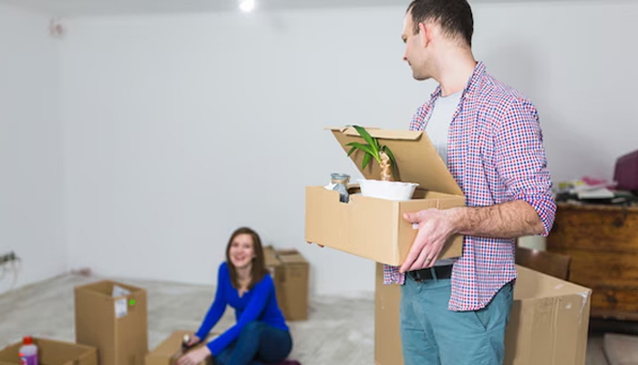 Man looking at woman sealing boxes