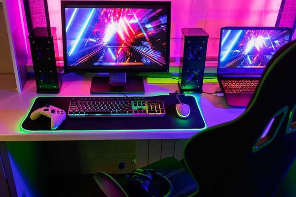 View of neon illuminated gaming desk setup with keyboard 