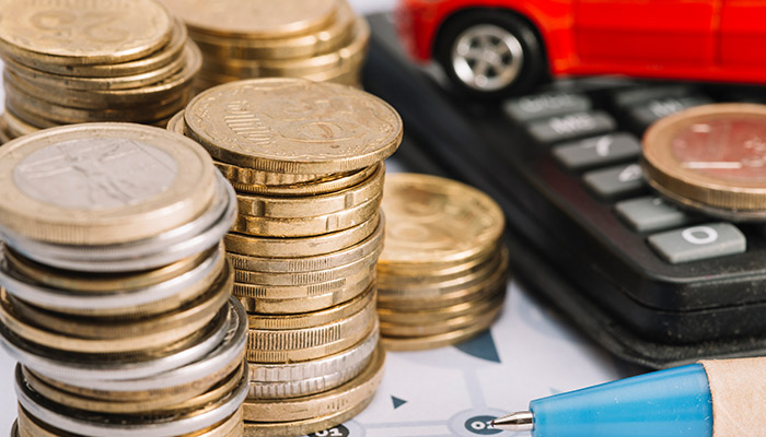 Close-up of stacked coins; pen and calculator