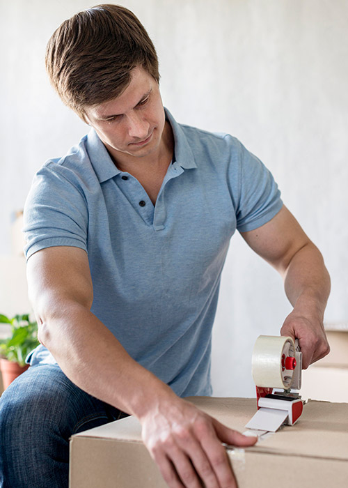 Man using scotch tape on box to secure it for moving out