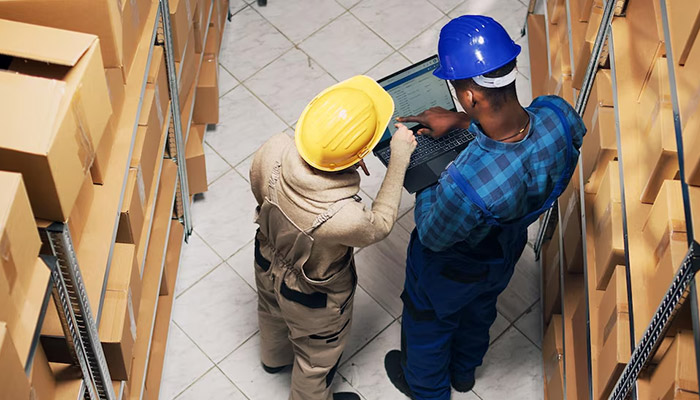 employees analyzing inventory list on laptop