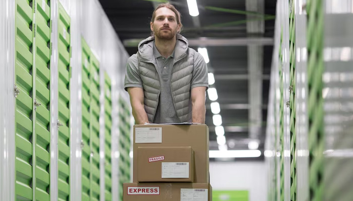 Man with boxes on a trolley walking in a storage facility