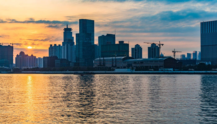 City Skyline By River Against Cloudy Sky