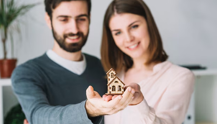 Blurred couple holding toy house