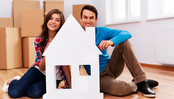 young couple with house sign