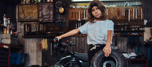 a child posing in a home garage with an ATV