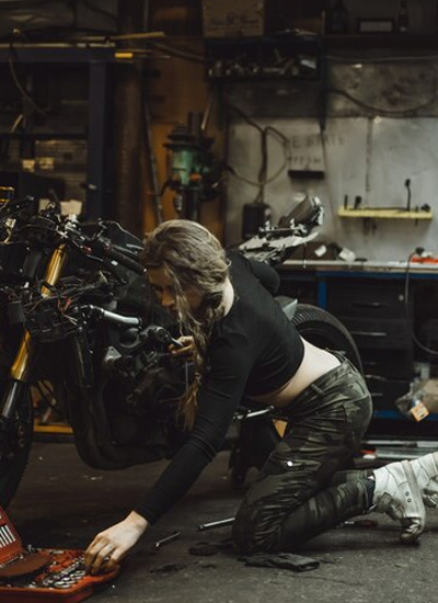 woman repairing motorcycle in a garage